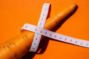 Carrot encircled by a measuring tape.