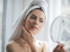 Woman looking at her face in the mirror.